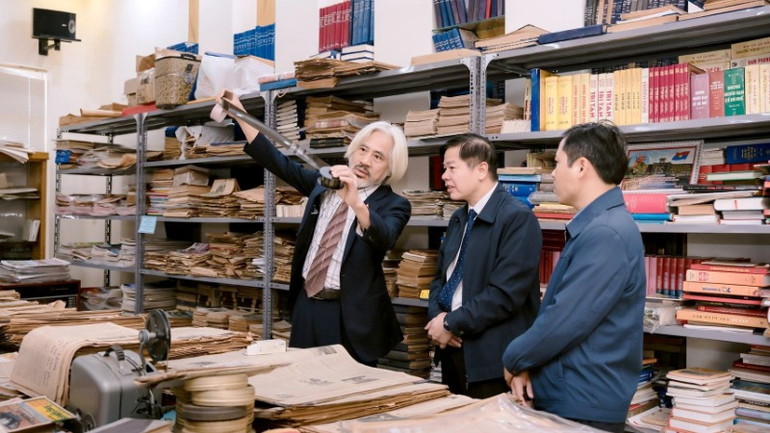 Ông Nguyễn Phi Dũng giới thiệu với khách tham quan những tờ báo giấy đã sưu tầm được.