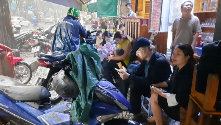 Người đi đường trú mưa chật kín quán cà-phê trên đường Lê Lai, quận 1.