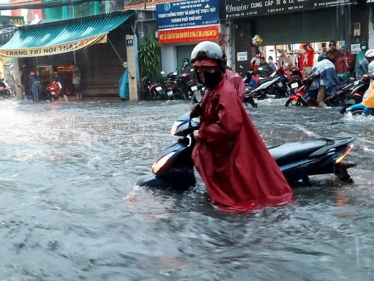 Người dân lội bì bõm, dắt xe trong cơn mưa chiều 15/5 khu vực đường Nguyễn Thị Rành, thành phố Thủ Đức