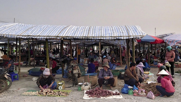 Người dân bày bán hàng trên khu đất lúa mà ông Nguyễn Hữu Phục tự ý đổ nền bê-tông, dựng lán tạm, nhà tôn. (Ảnh: THANH BÌNH)