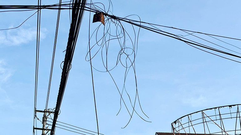 Rất nhiều dây cáp viễn thông bị đứt thòng xuống gần sát đường đi của người dân.