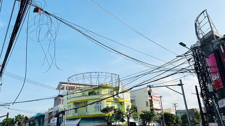 Dây điện, cáp viễn thông bị đứt treo lòng thòng xuống đường.