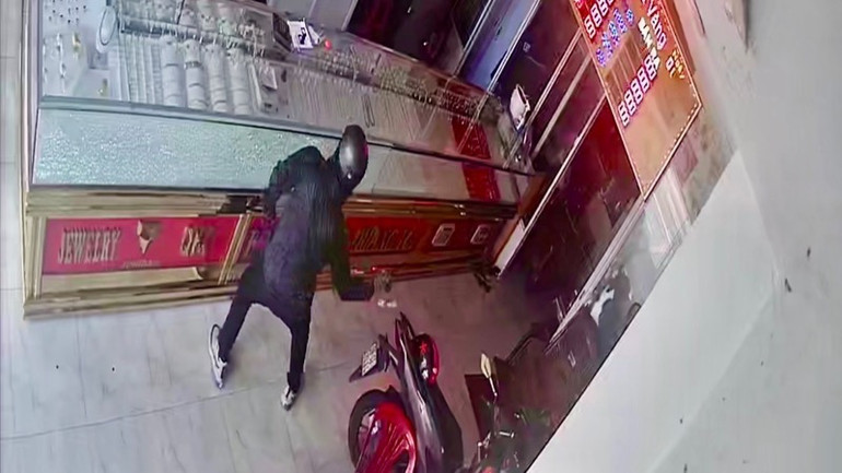 Một trong hai đối tượng dùng búa đập tủ kính cướp tài sản. (Ảnh cắt từ clip Công an cung cấp)