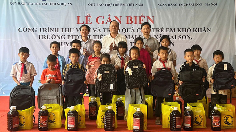 Đại diện Quỹ Bảo trợ trẻ em Việt Nam, các nhà hảo tâm tặng quà cho học sinh có hoàn cảnh khó khăn của Trường Phổ thông dân tộc bán trú tiểu học Mai Sơn. (Ảnh NFVC)