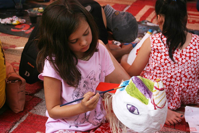Một em bé nước ngoài trải nghiệm vẽ đầu lân trong một dịp Trung thu do Bảo tàng Dân tộc học tổ chức. Trung thu và di sản tinh thần -0