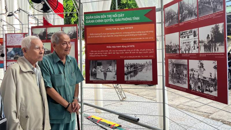 Ông Thức (trái) cùng cán bộ lão thành cách mạng xem hình ảnh lịch sử ngày giải phóng miền nam, thống nhất đất nước. (Ảnh: HOÀNG TRUNG)