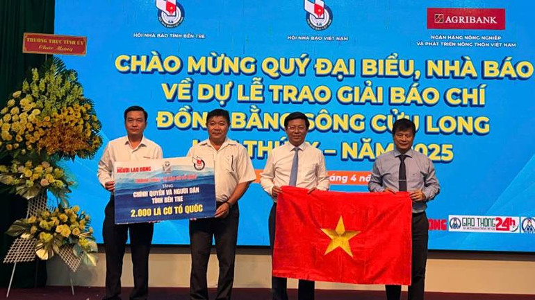 Đại diện Báo Người lao động trao cờ Tổ quốc cho chính quyền và người dân tỉnh Bến Tre. (Ảnh: HOÀNG TRUNG)