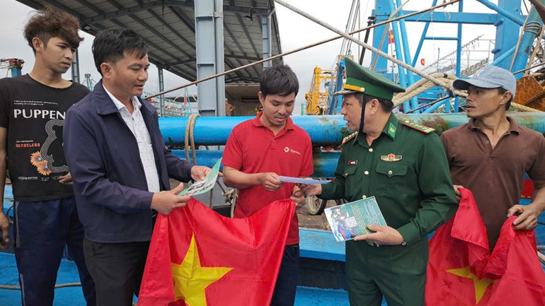 Đồng chí Nguyễn Bá Bình (thứ 2 từ trái qua phải), Phó Chính ủy Bộ đội Biên phòng tỉnh Bình Định trao cờ và tờ rơi tuyên truyền chống khai thác IUU cho ngư dân.