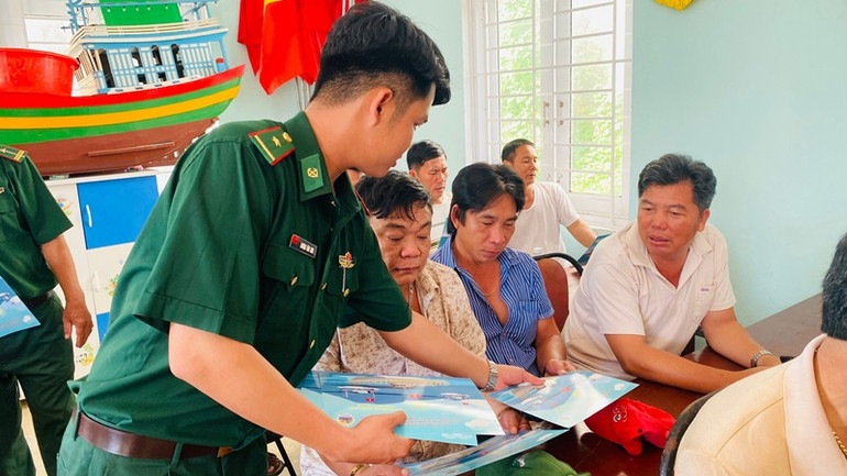 Cán bộ Đồn Biên phòng Mỹ An cấp phát tờ rơi cho ngư dân.