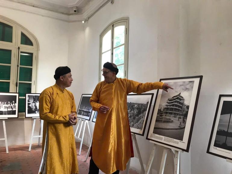 Hai nhiếp ảnh gia trò chuyện bên các tác phẩm.