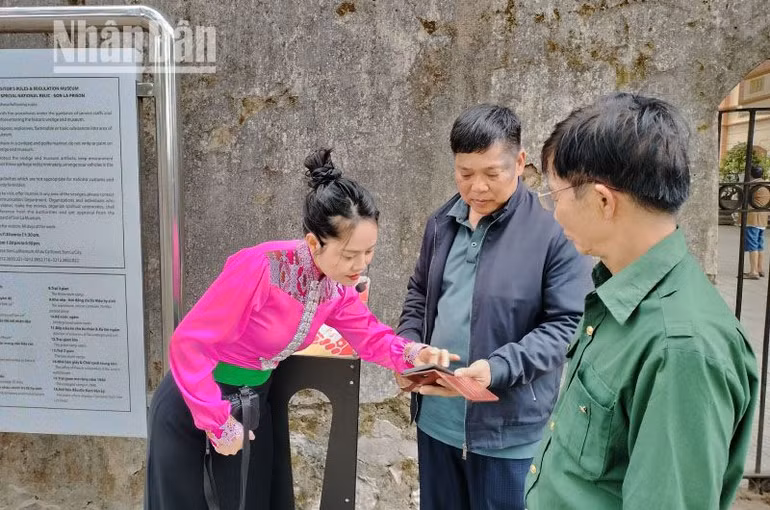 Hướng dẫn viên tại Khu di tích Quốc gia đặc biệt Nhà tù Sơn La đang hướng dẫn khách du lịch tương tác với công nghệ số không dây để truy cập vào trang web “Yêu lắm Việt Nam”.