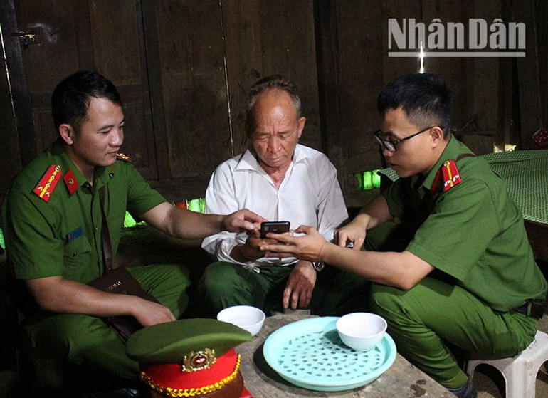 Đại úy Hoàng Văn Đông, Phó trưởng Công an xã Hồng Ngài (bên trái) cùng đồng nghiệp tuyên truyền về tiện ích của định danh điện tử cho người dân.