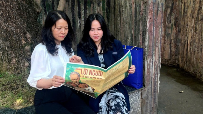 Cô giáo và phụ huynh đọc chung một trang báo - khoảnh khắc đáng nhớ của hành trình.