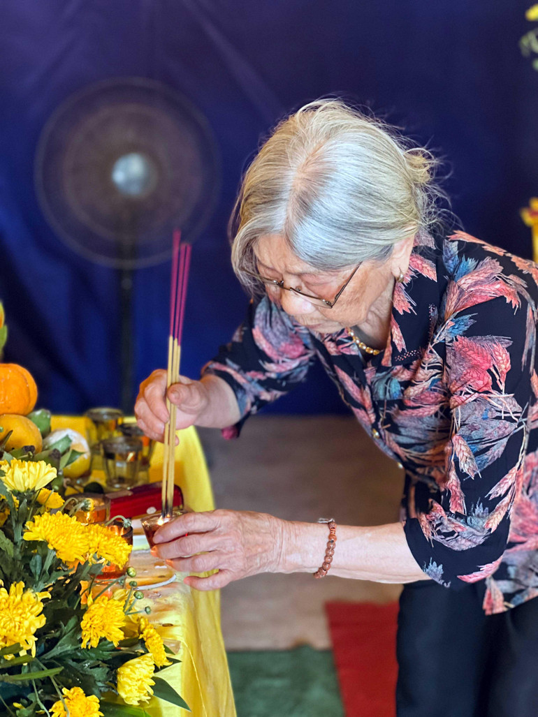 Mẹ liệt sĩ Phạm Văn Sự thắp nén hương trong ngày đón con trai về lại quê hương. (Ảnh LAN VŨ)