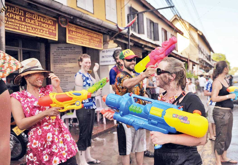 Du khách nước ngoài tham gia té nước cầu may. Ảnh | QUANG PHÚC