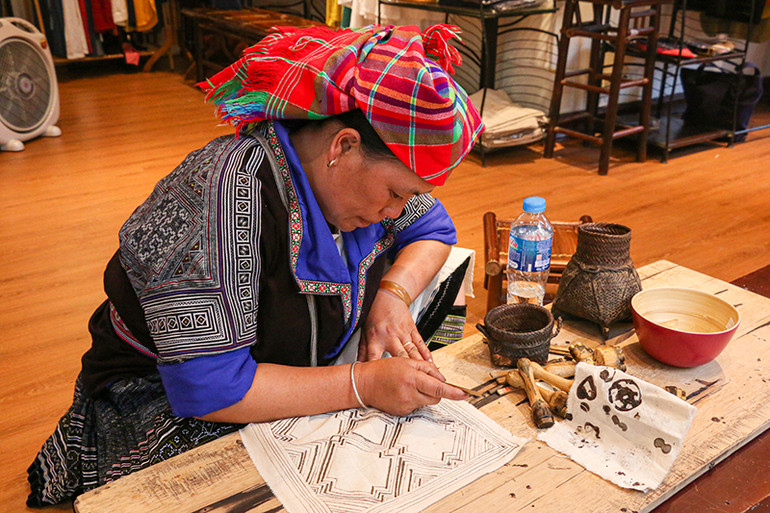 Nghệ nhân người H’Mông vẽ sáp ong trên vải lanh. (Ảnh: Hà Nam)