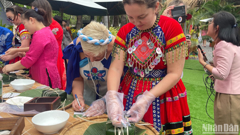 Khách nước ngoài đang hoàn thiện gói chiếc bánh chưng.