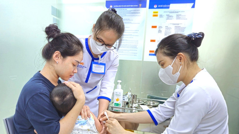 Phụ huynh đưa con em đến tiêm vắc xin phòng, chống bệnh sởi.