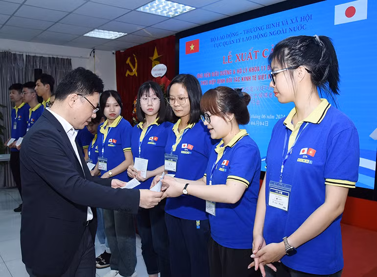 Phó Cục trưởng Cục Quản lý lao động ngoài nước Đặng Sĩ Dũng trao chứng chỉ cho các ứng viên tại lễ xuất cảnh. (Ảnh: TRẦN HẢI)