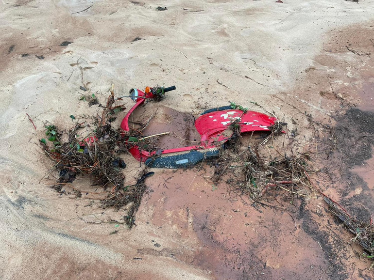 Một chiếc xe máy nằm dưới đống cát.