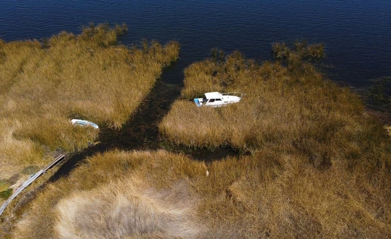 Một góc hồ Titicaca trong mùa hạn hán. Bờ sông cây cỏ cằn khô và độ sâu của hồ đang bị thu hẹp đến báo động. Ảnh: Reuters.