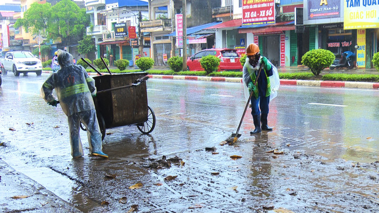 Công nhân môi trường đô thị không kể mưa lớn để làm cho đường phố sạch đẹp trở lại.