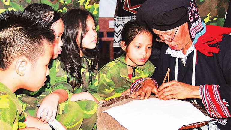 Các em nhỏ trải nghiệm trực tiếp cách nghệ nhân người Dao in hoa văn bằng sáp ong.