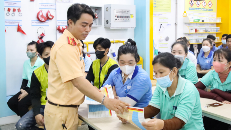 Cán bộ Phòng Cảnh sát giao thông, Công an thành phố phát tờ rơi tuyên truyền về những điểm mới của Nghị định 168/2024/NĐ-CP cho người lao động.