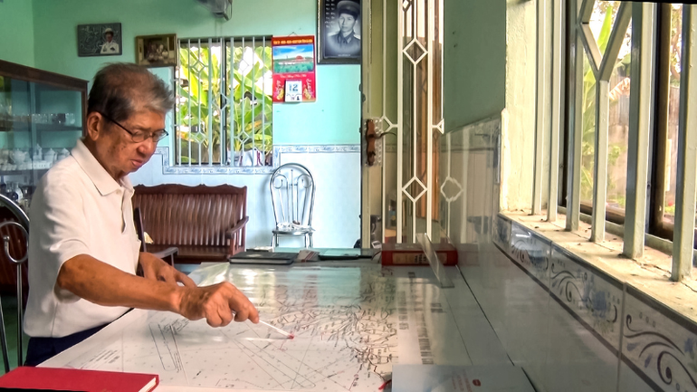 Đại tá Khưu Ngọc Bảy, nguyên Trung đoàn trưởng Trung đoàn 962, Quân khu 9 hướng dẫn cho phóng viên điểm tập kết vũ khí tại bến Vàm Lũng trên bản đồ.