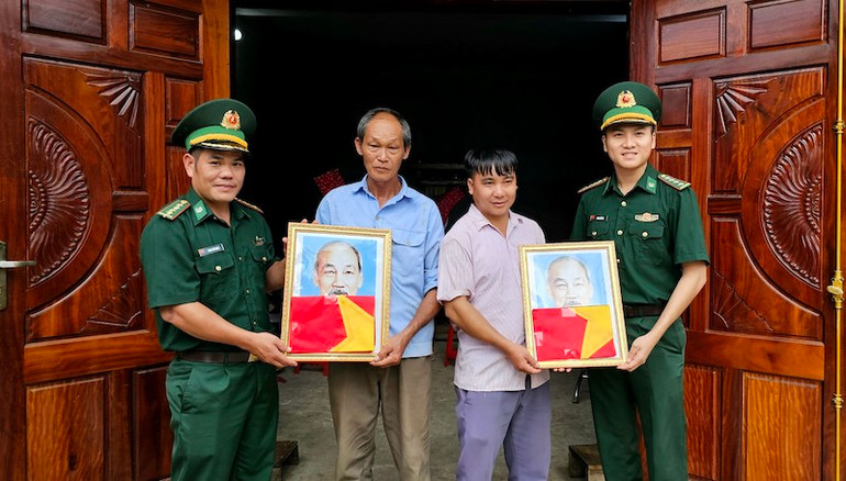 Cán bộ Trạm Biên phòng Cửa khẩu Hoành Mô tặng cờ và ảnh Bác Hồ cho người dân thôn Phai Lầu, xã Hoành Mô, Bình Liêu.
