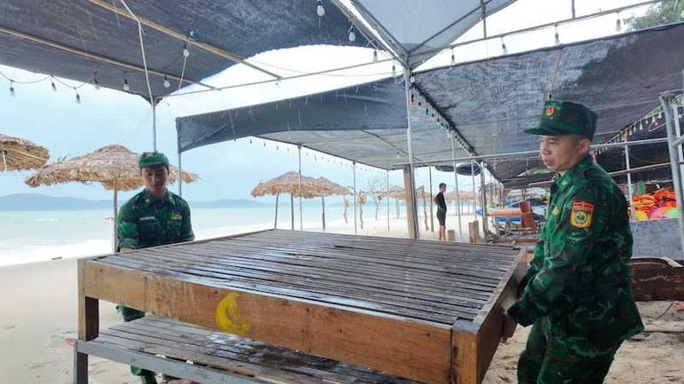 Cán bộ, chiến sĩ Đồn Biên phòng Cô Tô giúp người dân thu dọn tài sản, chằng chống hàng quán kinh doanh trên bãi biển.