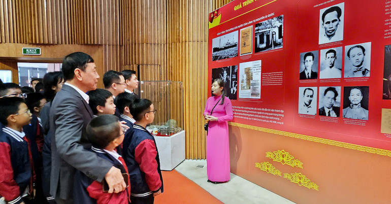 Các đại biểu và các em học sinh nghe thuyết minh về truyền thống vẻ vang của Đảng Cộng sản Việt Nam trong 95 năm qua.