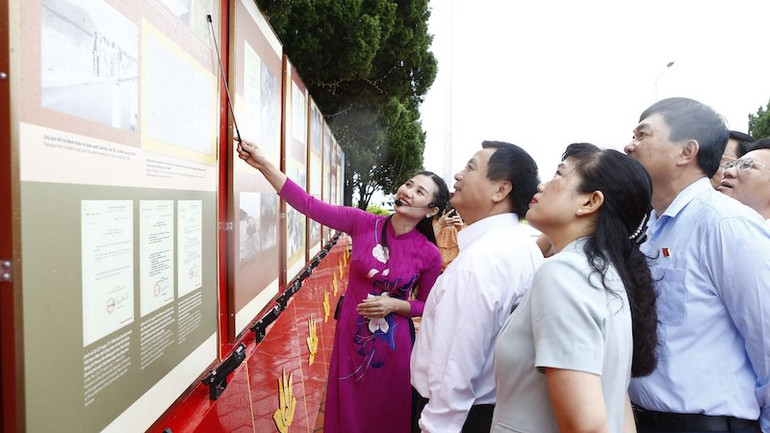 Đồng chí Nguyễn Xuân Thắng và các đại biểu tham quan và nghe giới thiệu về Triển lãm "Sưu tầm chữ ký và bút tích của Chủ tịch Hồ Chí Minh" trên đảo Cô Tô.