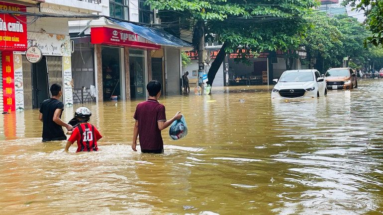 Người dân chạy lũ tại đường Thành Công, phường Nguyễn Thái Học, thành phố Yên Bái. (Ảnh: THANH SƠN)