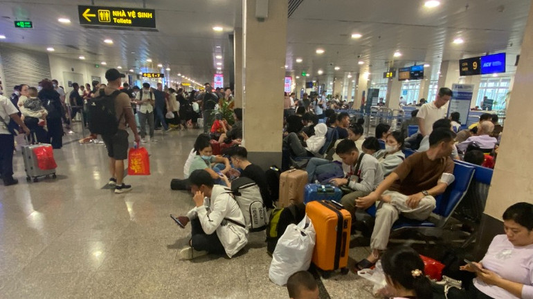 Hành khách ngồi la liệt dưới đất chờ đến giờ bay. (Ảnh: QUÝ HIỀN) Hành khách ngồi la liệt dưới đất chờ đến giờ bay. (Ảnh: QUÝ HIỀN)