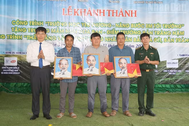 Lãnh đạo Ban Chỉ huy Bộ đội Biên phòng tỉnh Sơn La và xã Yên Sơn tặng ảnh Bác Hồ và cờ Tổ quốc cho các bản.
