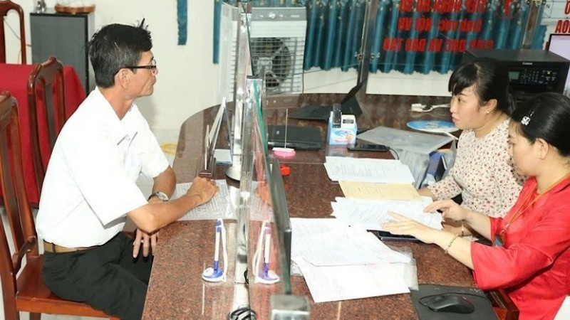 Cán bộ xã hướng dẫn thủ tục hành chính cho người dân. (Ảnh: Báo Nhân Dân)