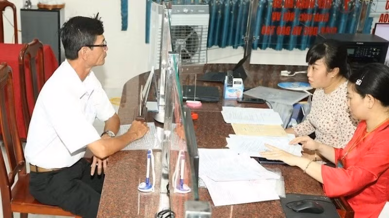 Cán bộ xã hướng dẫn thủ tục hành chính cho người dân. (Ảnh: Báo Nhân Dân)