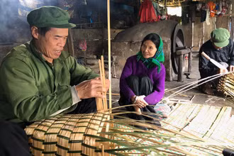 Ông Lâm A Liên và ông Lâm A Diện đang đan gùi trong căn bếp nhà mình.