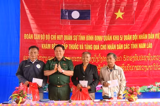 Đại tá Nguyễn Xuân Sơn, Phó Chính ủy Bộ Chỉ huy Quân sự tỉnh Bình Định tặng quà cho nhân dân ở cụm bản La Nhao, huyện Xá Mắc Khi Xay, tỉnh Attapu.