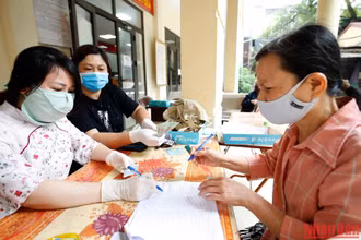 Người lao động nhận tiền hỗ trợ do ảnh hưởng vì dịch Covid-19. (Ảnh: Duy Linh)