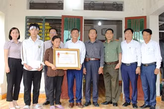 Đại diện đoàn công tác trao Huân chương Dũng cảm cho người thân anh Phạm Ngọc Anh.