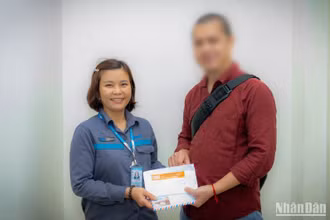 Chị Tươi trao lại chiếc túi chứa 4.300 USD cho anh V.Q.Đ. trong niềm vui sướng của anh.