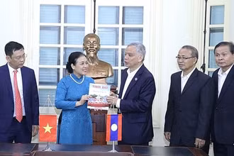 Bà Nguyễn Phương Nga tặng Chủ tịch Ủy ban Hòa bình và Đoàn kết Lào Sommad Pholsena cuốn đặc san "60 năm hữu nghị Việt Nam-Lào: Chung dãy Trường Sơn" của Tạp chí Thời Đại. (Nguồn: Báo Hà Nội mới)