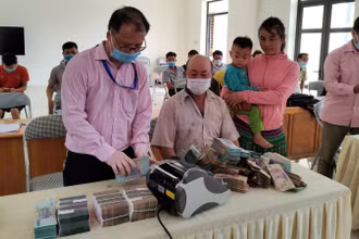 Cán bộ Ngân hàng Chính sách xã hội giúp bà con xếp gọn tiền trước khi gửi tiết kiệm tại Điểm giao dịch.