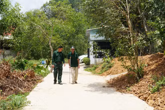 Hai cha con ông Bùi Văn Tượng đi trên con đường mới từ một phần đất gia đình đóng góp.