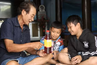 Nghệ nhân Trần Ngọc Vinh và các cháu bên sản phẩm nước mắm của gia đình. 