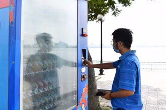 Người dân mua nước uống có đường tại máy bán nước tự động trên địa bàn thành phố Hà Nội. (Ảnh MỸ HÀ) 