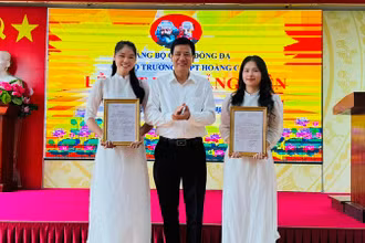 Phó Bí thư Thường trực Quận ủy Đống Đa Nguyễn Anh Cường trao quyết định kết nạp đảng viên cho hai học sinh ưu tú Trường THPT Hoàng Cầu.