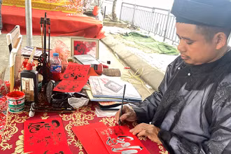 Anh Trần Hậu Thao viết chữ thư pháp tại khu di tích Đền Ông Hoàng Mười (Nghệ An).